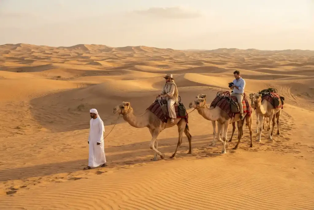 Tourists enjoying a camel ride across golden dunes during a Dubai desert safari
